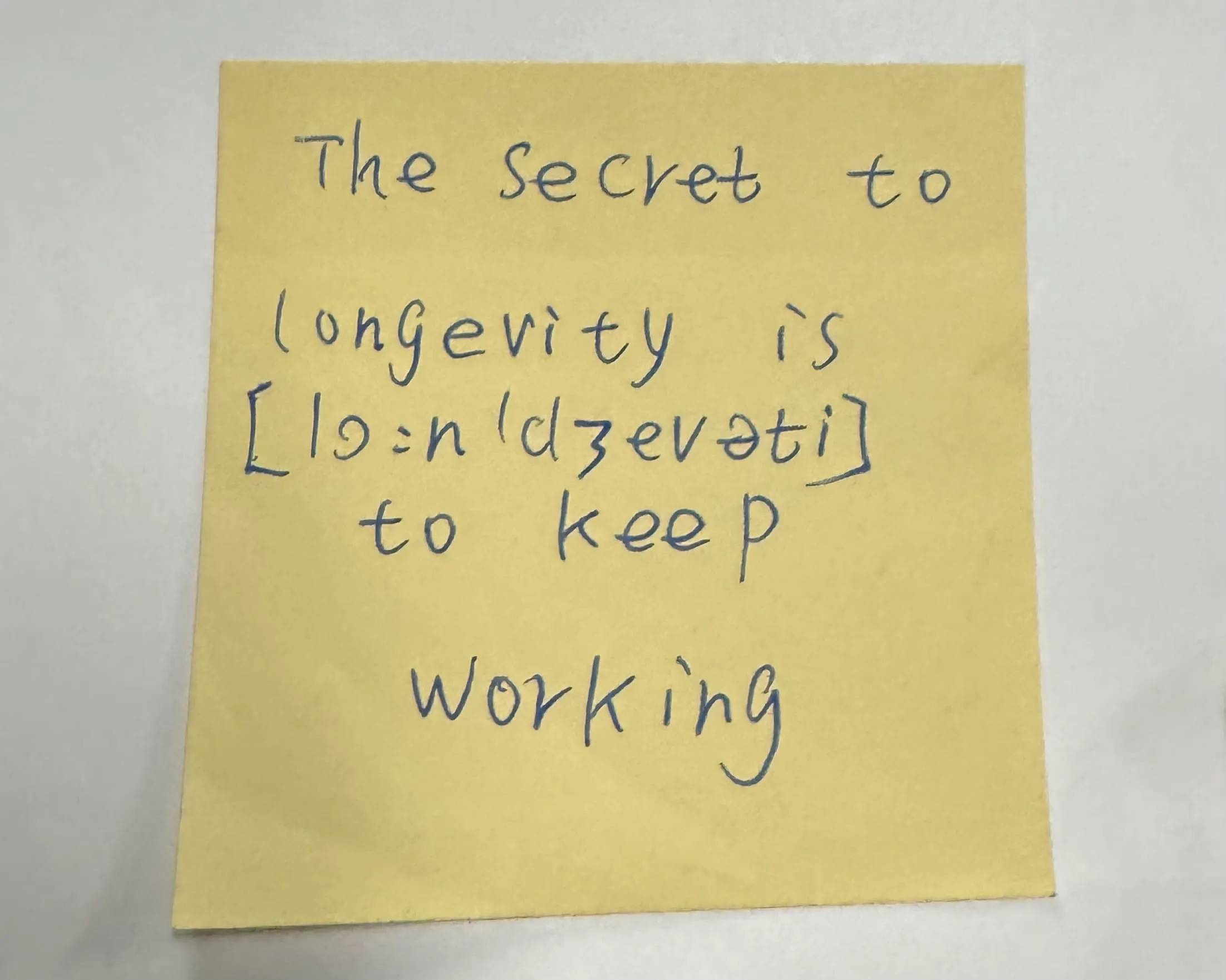 A sticky note that says the secret to longevity is to keep working.